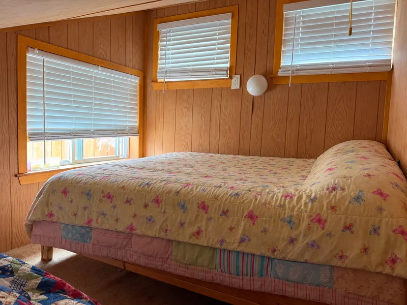 The loft: a wide bed under the windows, wood-panelled walls